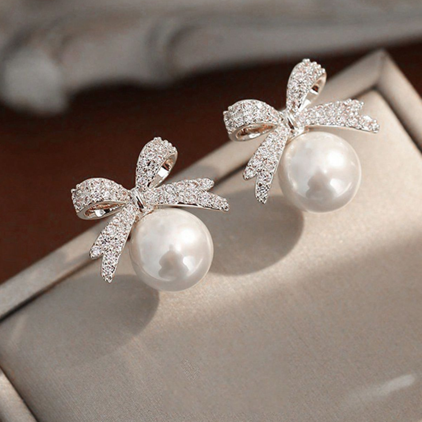 Rhinestone and faux pearl bow stud earrings.