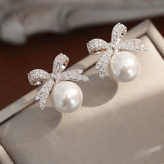 Rhinestone and faux pearl bow stud earrings.