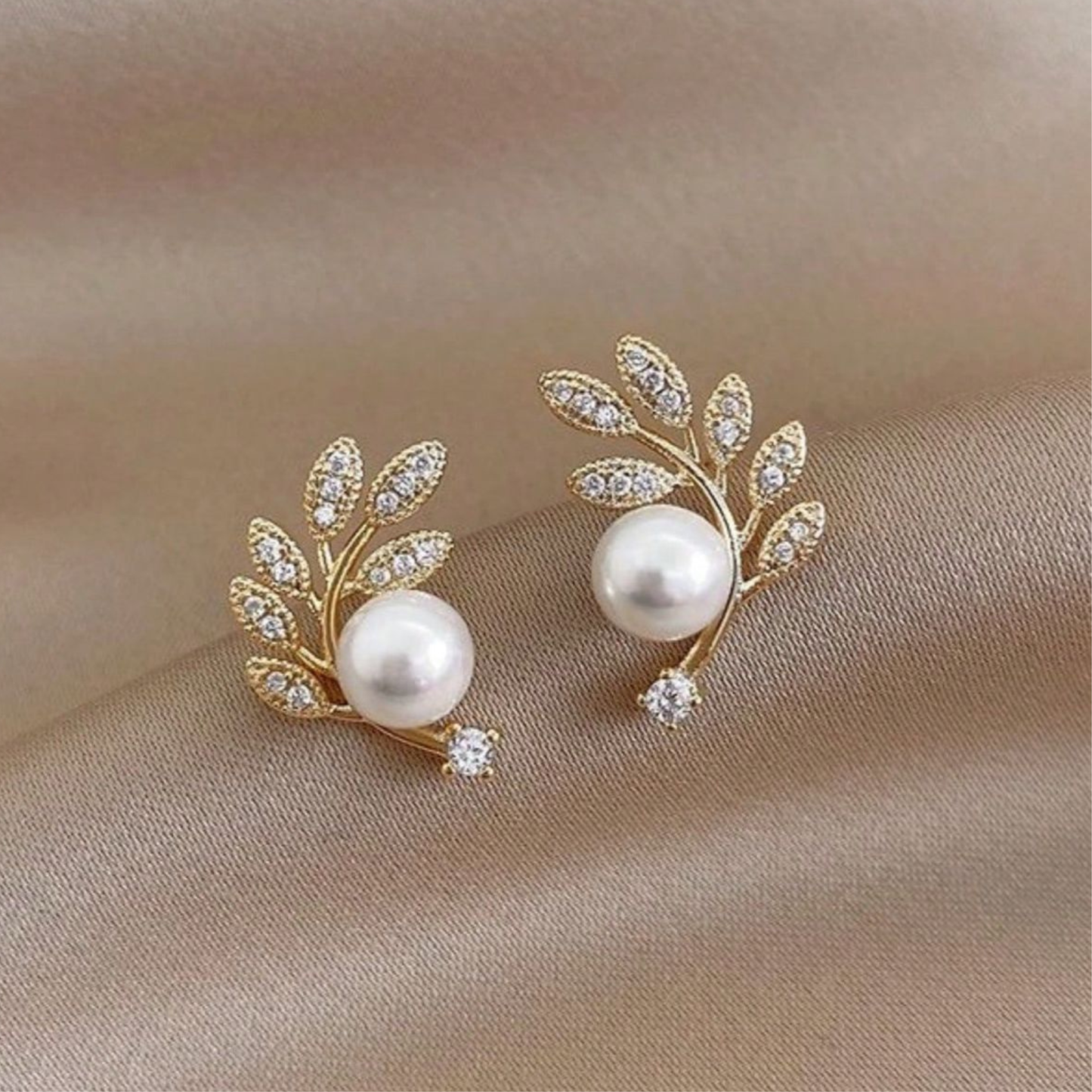 Gold-toned, leaf-shaped stud earrings featuring simulated pearls and cubic zirconia accents.